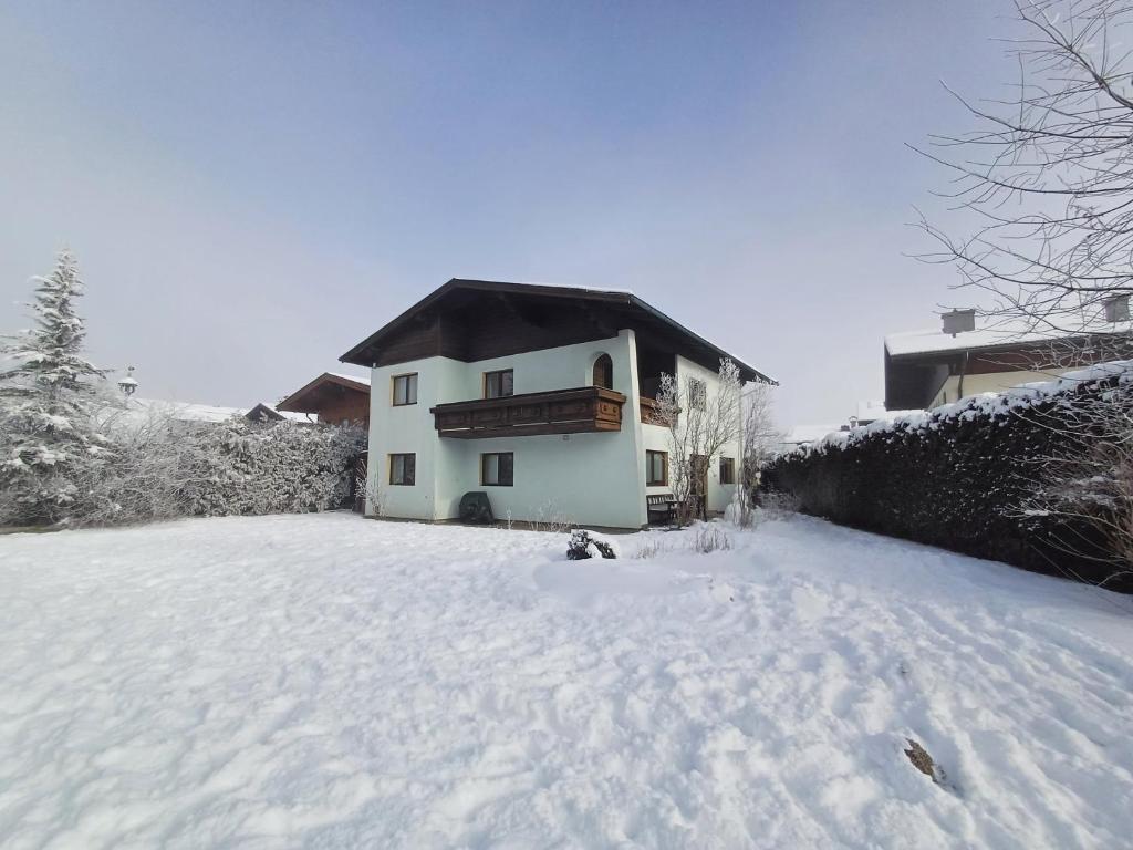 un cortile coperto da neve con una casa sullo sfondo di Hochtenn Lodge in Zell am See - Steinbock Lodges a Zell am See