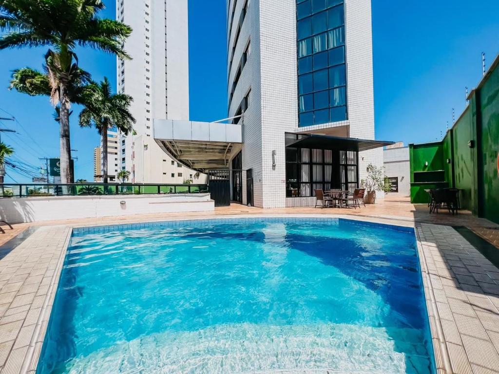 a swimming pool in front of a building at Natal Plaza Suítes- Ponta Negra in Natal