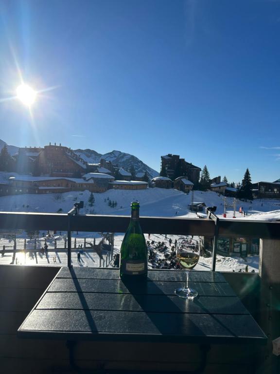 een fles wijn zittend op een tafel met een glas bij Hygge Ski-in-Ski-out med udsigt in Avoriaz