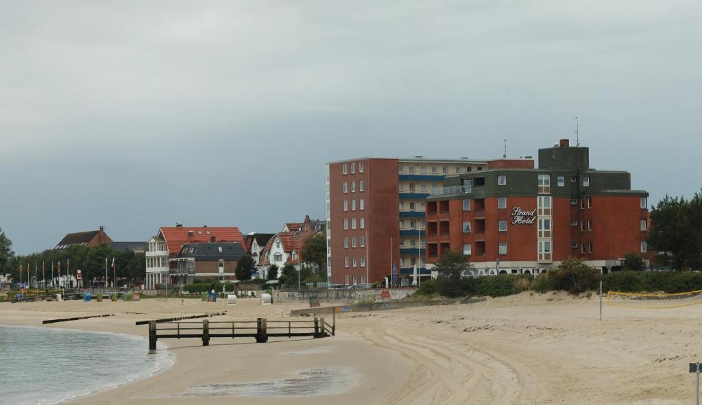 een uitzicht op een strand met gebouwen op de achtergrond bij Strandhotel in Wyk auf Föhr