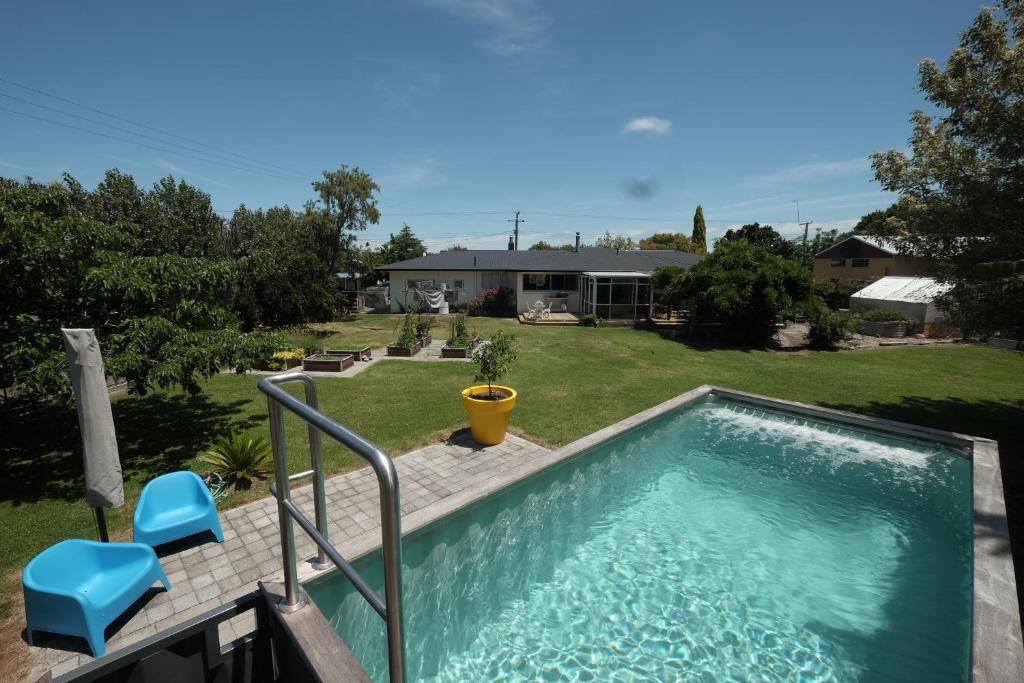 uma piscina com duas cadeiras azuis e uma casa em Evendale House em Hastings