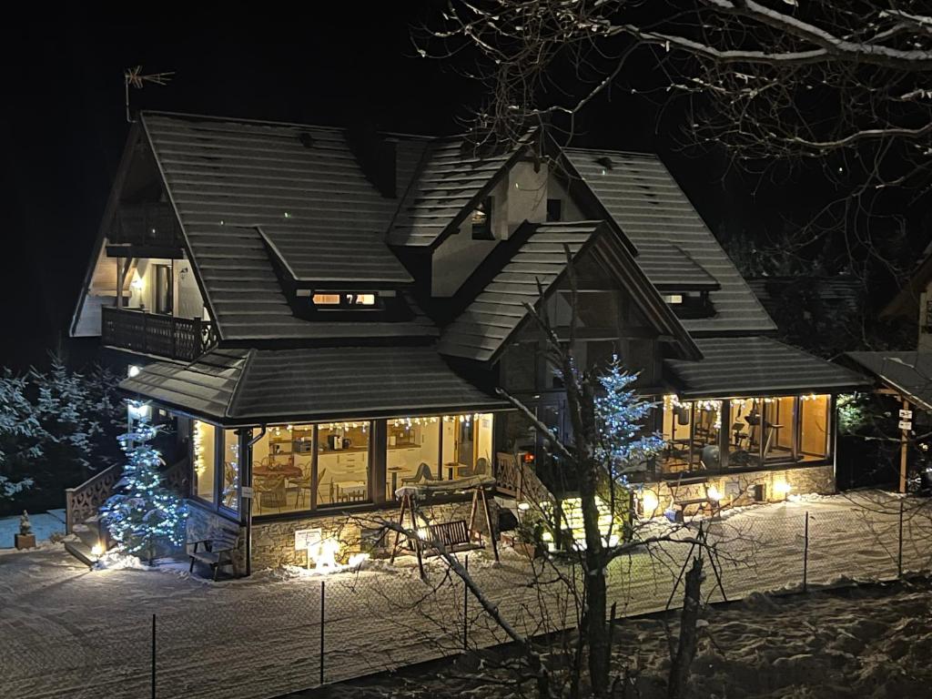 Una casa por la noche con luces en la nieve en Willa FOLK Pieniny, en Szczawnica