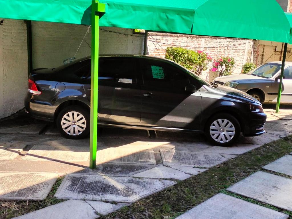 um pequeno carro preto estacionado sob um guarda-chuva verde em Casa Lili em Cuernavaca