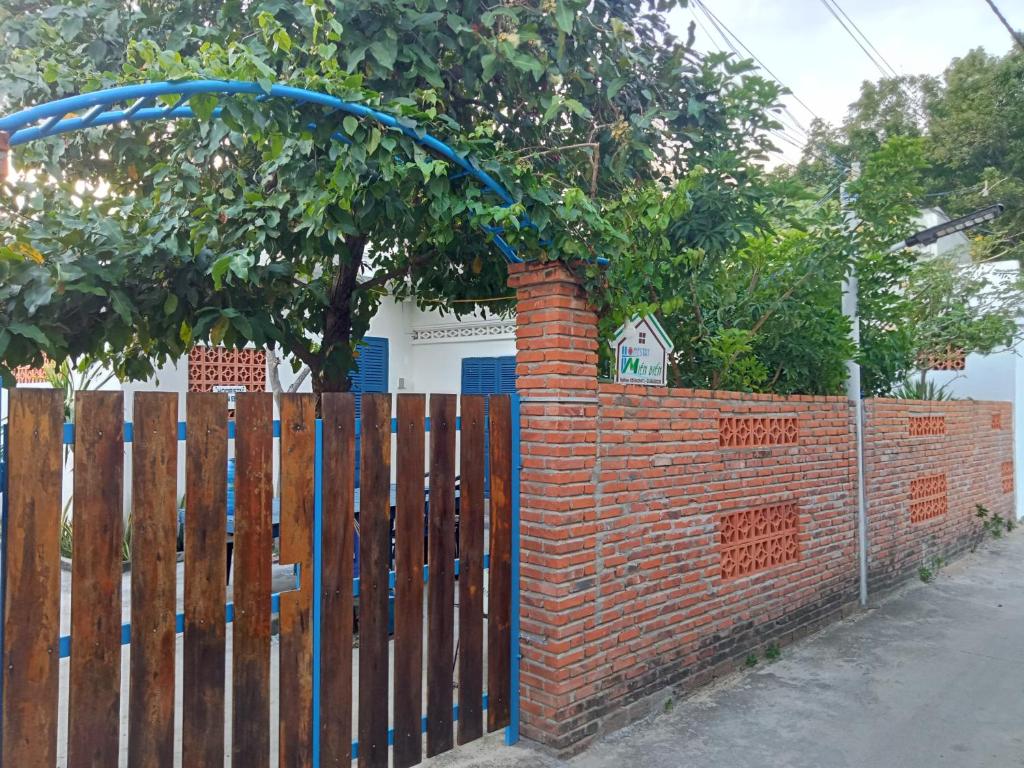 una cerca de ladrillo con una puerta con un árbol detrás de ella en Homestay Miền Biển Vĩnh Hy 2, en Vĩnh Hy