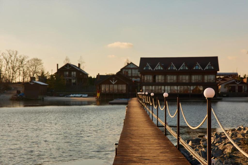 a wooden boardwalk leading to a building on a lake at Waterloo Village in Pidhorodne