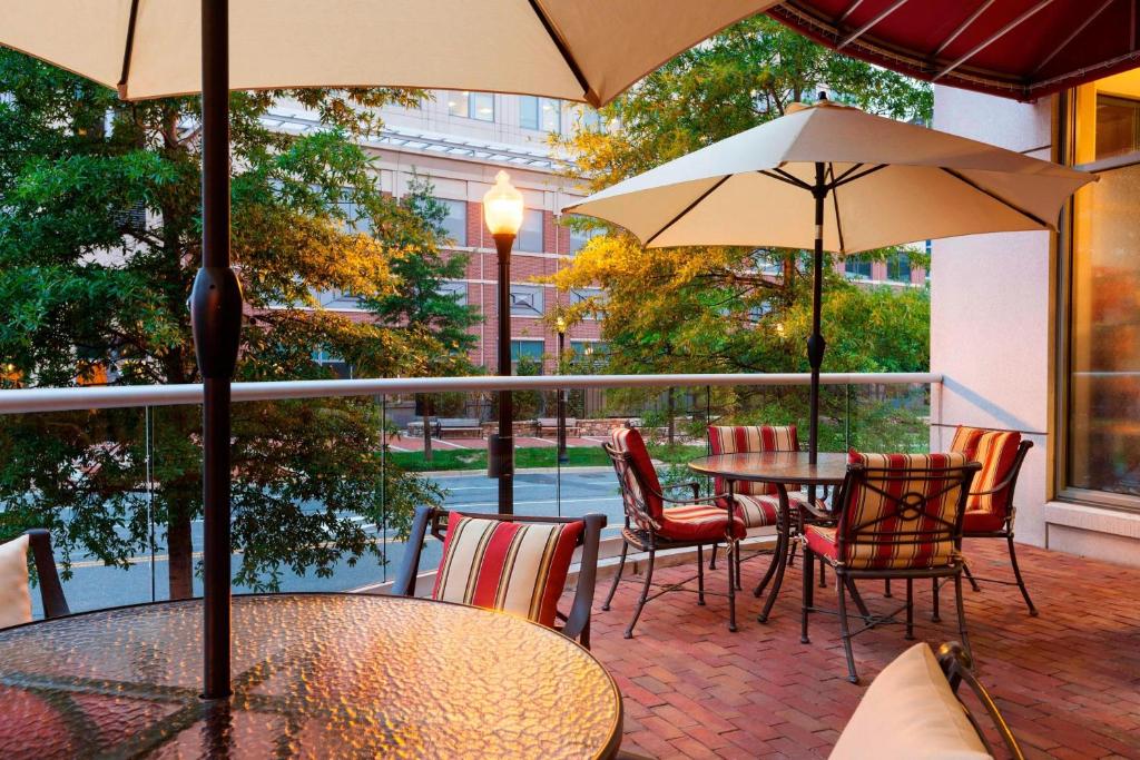 eine Terrasse mit Tischen, Stühlen und Sonnenschirmen in der Unterkunft Residence Inn Alexandria Old Town South at Carlyle in Alexandria