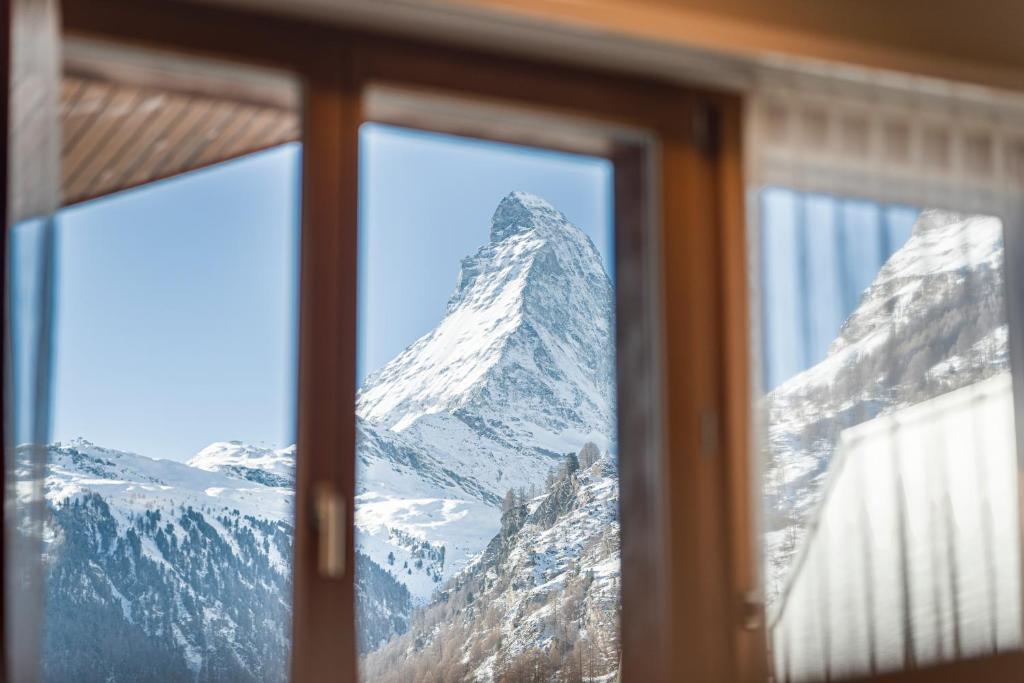 a view of a snow covered mountain through a window at Hotel Parnass in Zermatt