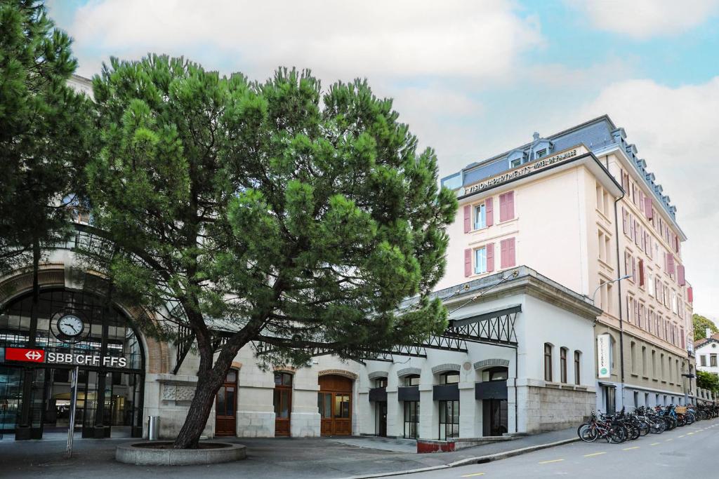 un grande edificio bianco con un albero di fronte di VISIONAPARTMENTS Rue des Communaux - contactless check-in a Vevey