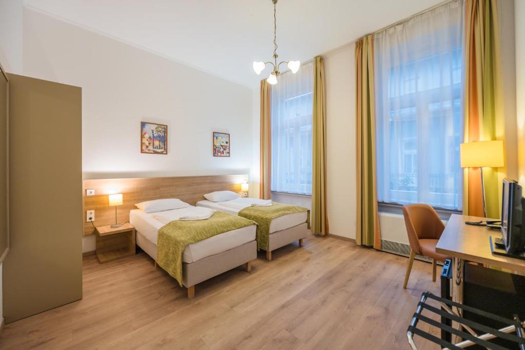 Baross City Hotel - Budapest في بودابست: غرفة فندقية بسريرين ومكتب