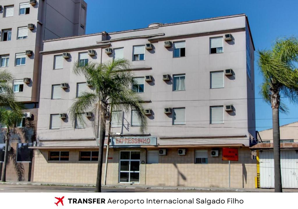 Hotel Expressinho Aeroporto في بورتو أليغري: عماره امامها نخيل