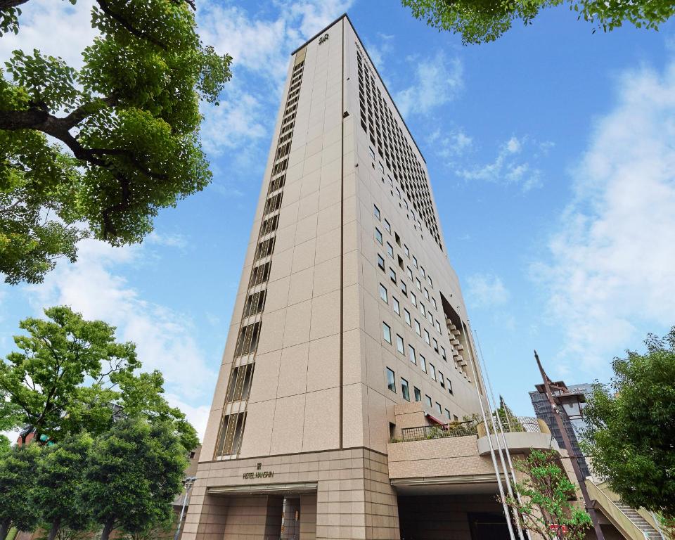 un alto edificio bianco con alberi di fronte di Hotel Hanshin Osaka ad Osaka