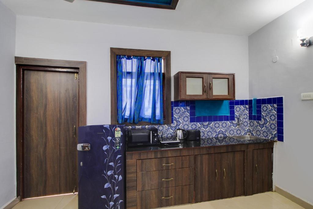 una cucina con lavandino e parete piastrellata blu di Capital O Royale Palms a Benaulim