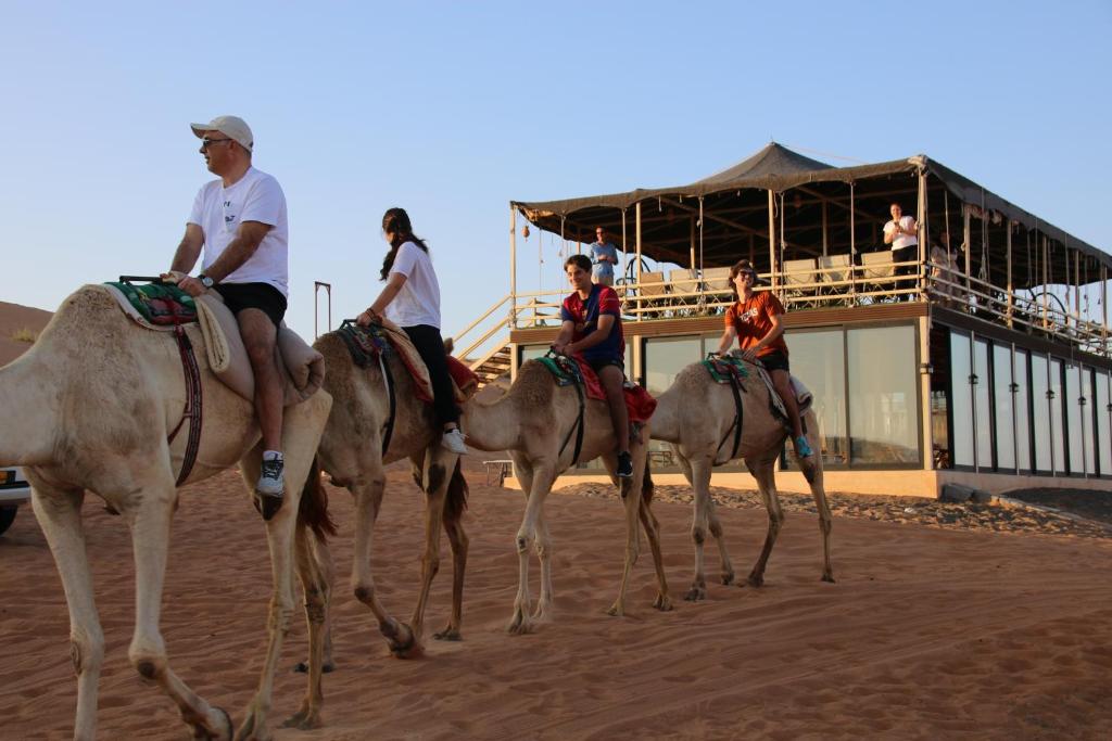 a group of people riding on horses in the desert at Oman desert private camp in Shāhiq