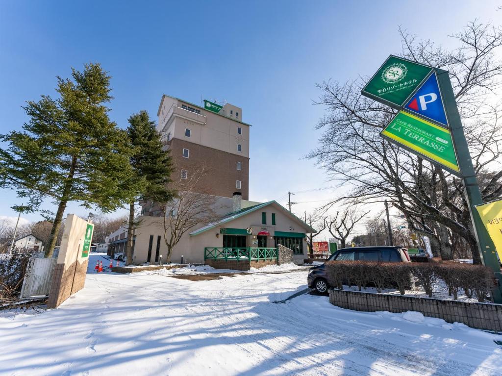 a parking sign in the snow next to a building at Tabist Shizukuishi Resort Hotel in Shizukuishi