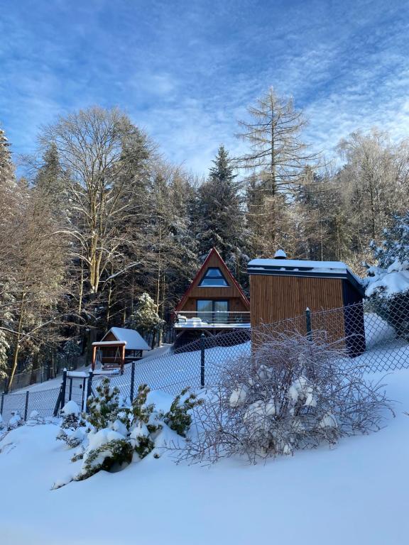 une cabine dans la neige avec une clôture dans l'établissement Duszek Lasu, à Brenna