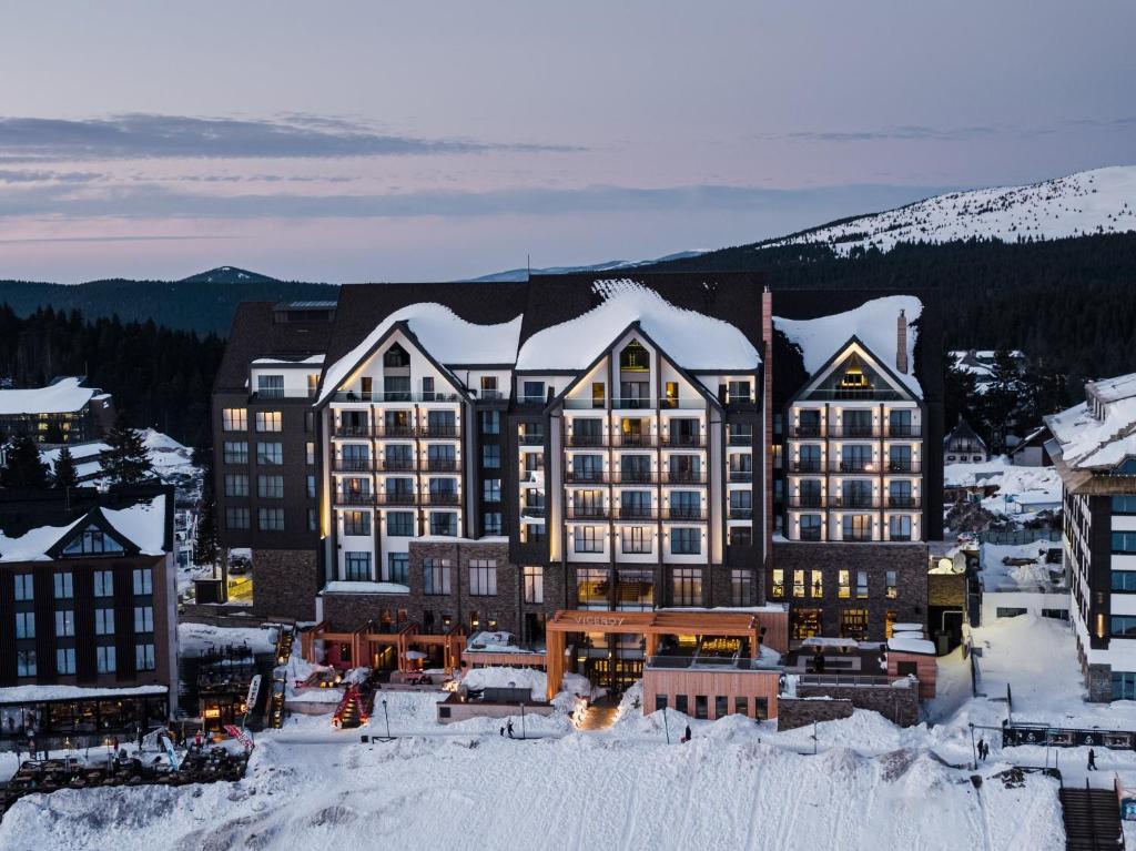 ein großes Gebäude mit Schnee auf einer Stadt in der Unterkunft Viceroy Kopaonik Serbia in Kopaonik