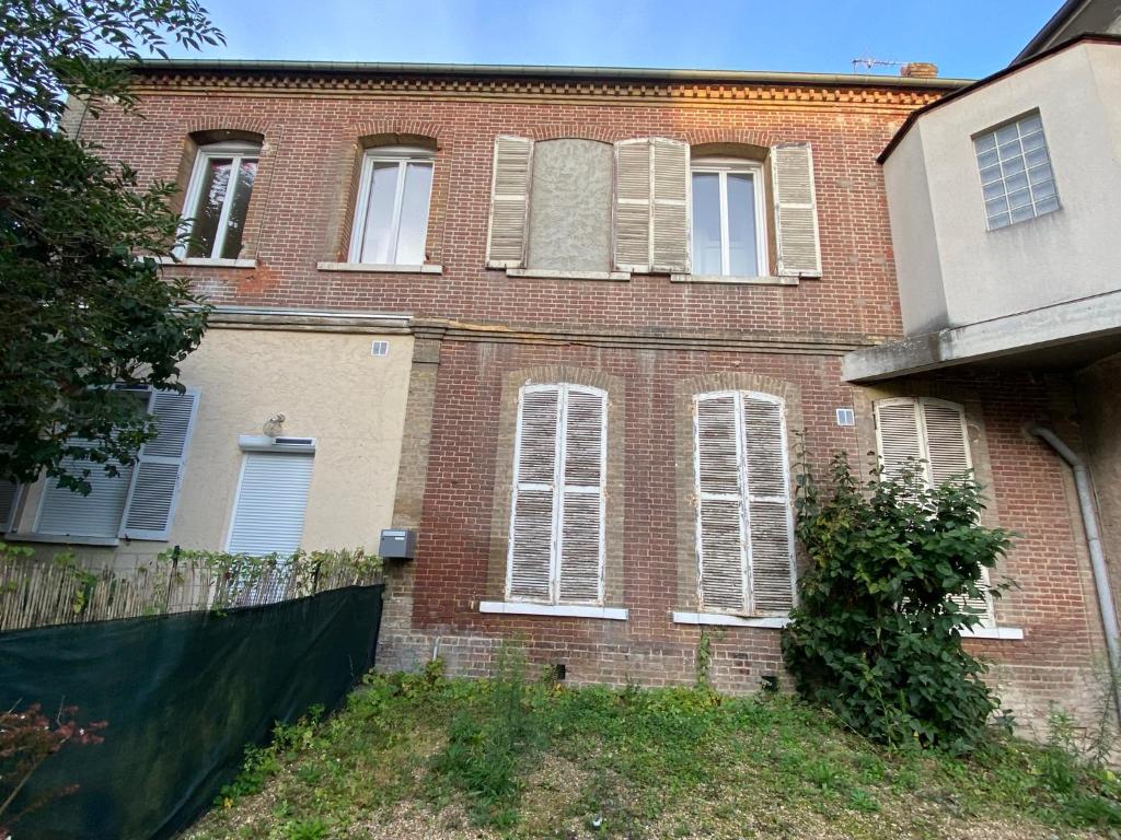 una casa de ladrillo con ventanas blancas y una valla en Jungle Cosy, en Louviers