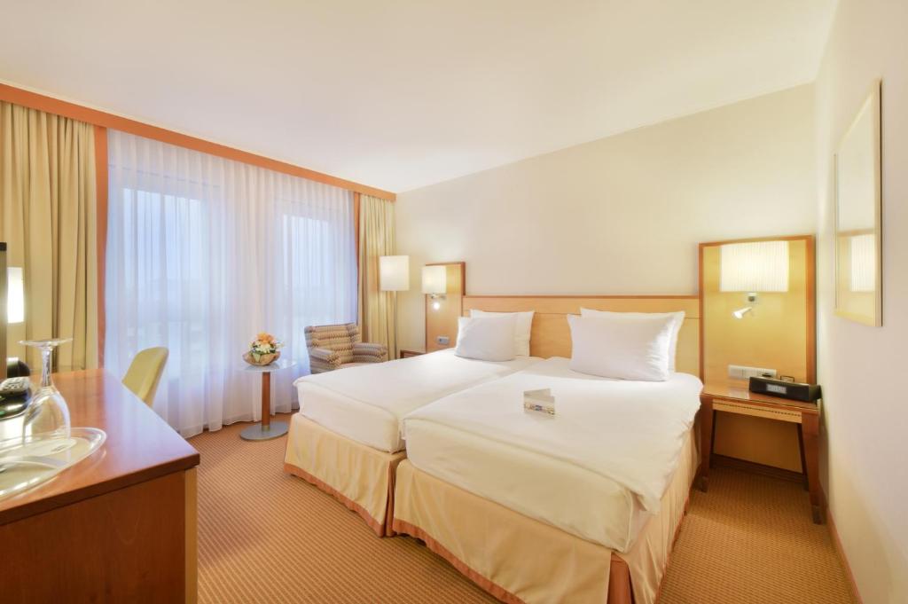 a hotel room with a large bed and a bathroom at The Q Quadro City Hotel in Karlsruhe