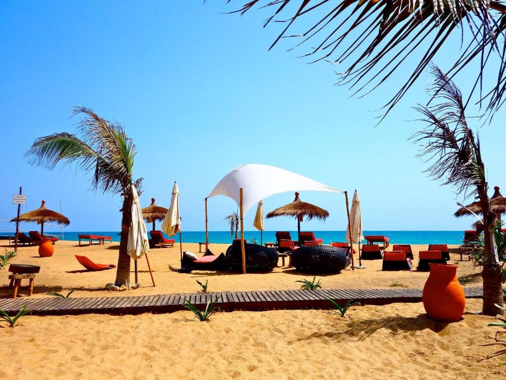 una spiaggia con sedie e ombrelloni e l'oceano di Pure Plage a Lomé