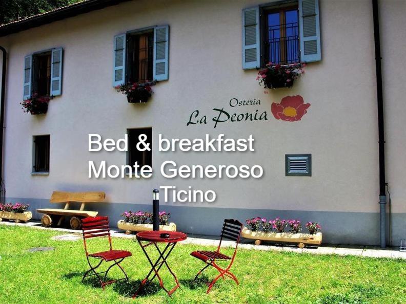 duas cadeiras e uma mesa em frente a um edifício em MOUNTAIN HOTEL Osteria di MONTAGNA La Peonia Monte Generoso em Mendrisio