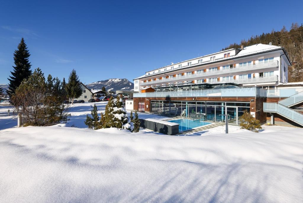 un edificio con piscina en la nieve en Hotel-Restaurant Grimmingblick, en Bad Mitterndorf