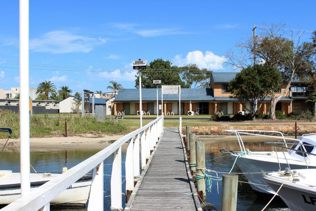 ein Dock mit zwei Booten, die neben einem Haus angedockt sind in der Unterkunft Lakeside Motel Waterfront in Lakes Entrance