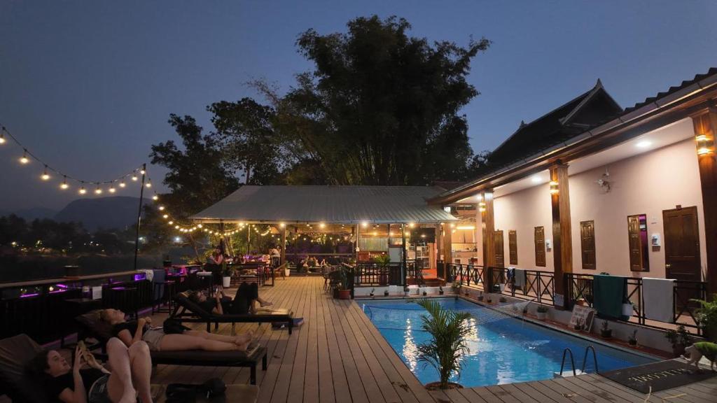 un grupo de personas sentadas alrededor de una piscina por la noche en Funny Riverside Backpackers, en Luang Prabang