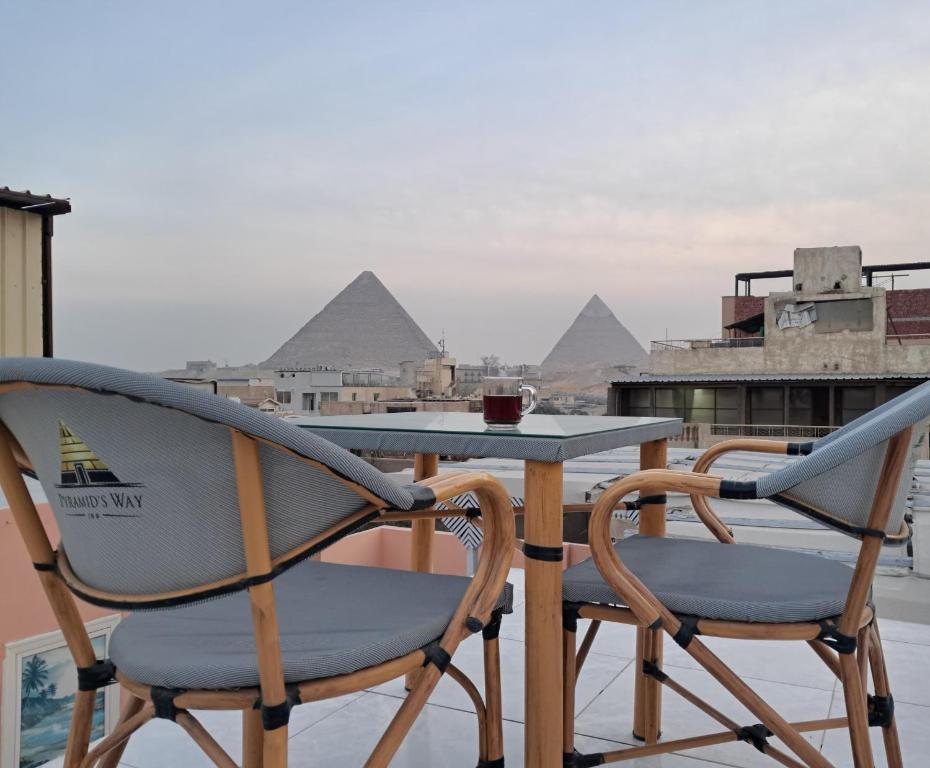 2 sedie e un tavolo sul balcone con piramidi di New pyramids way a Il Cairo