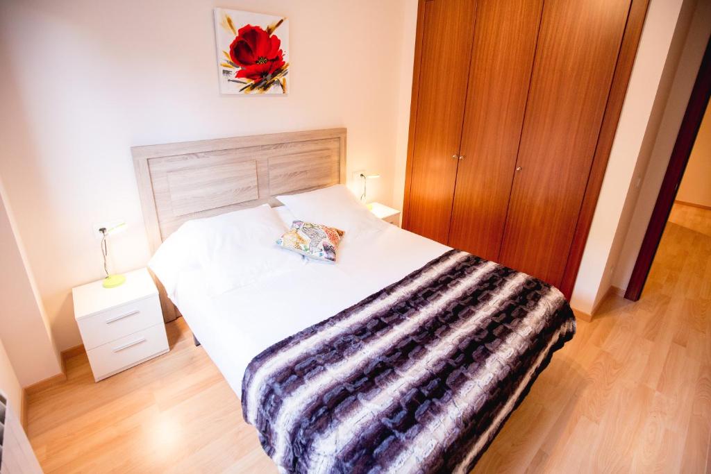 1 dormitorio con cama blanca y manta a rayas en Apartaments Ashome, en Canillo