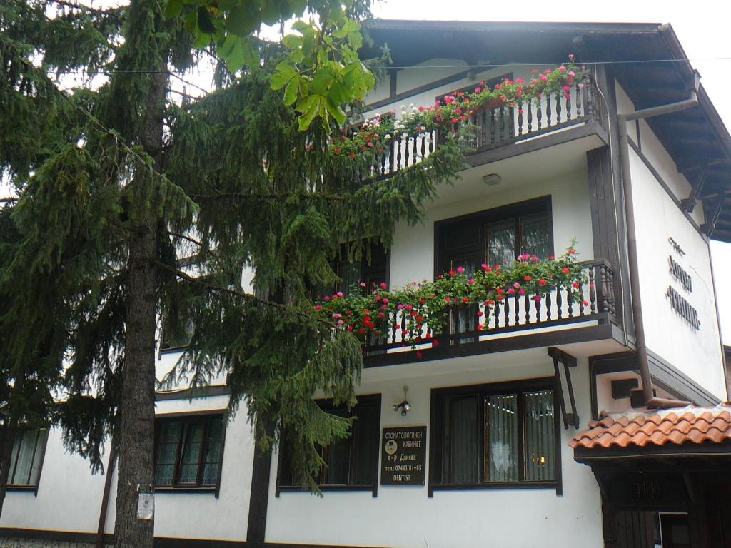 un edificio blanco con flores en los balcones en Къща за гости Типик, en Bansko