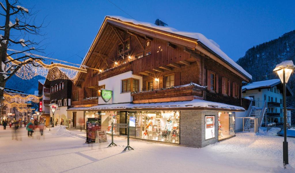 budynek w śniegu z ludźmi idącymi przed nim w obiekcie Schneider Hof Boutique-Hotel Garni Superior w mieście Sankt Anton am Arlberg