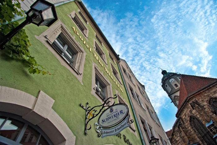 un edificio verde con un cartel en el costado en Schwerter Schankhaus & Hotel, en Meißen