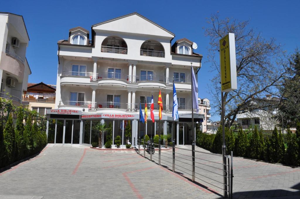 un grande edificio bianco con bandiere di fronte di Villa Dislievski a Ohrid