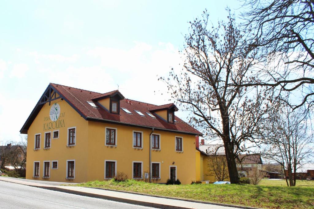 um edifício amarelo com um telhado vermelho ao lado de uma rua em Golf Hotel Karolina em Karlovy Vary