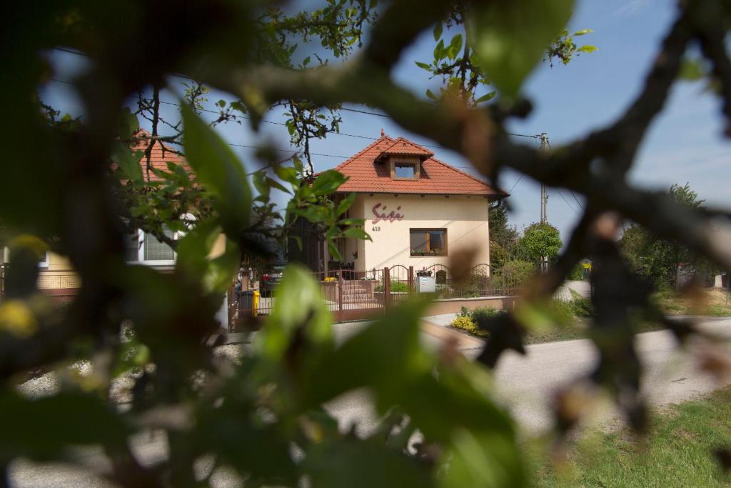 a house with a red roof seen through the trees at Rekreačný dom SISI in Podhájska