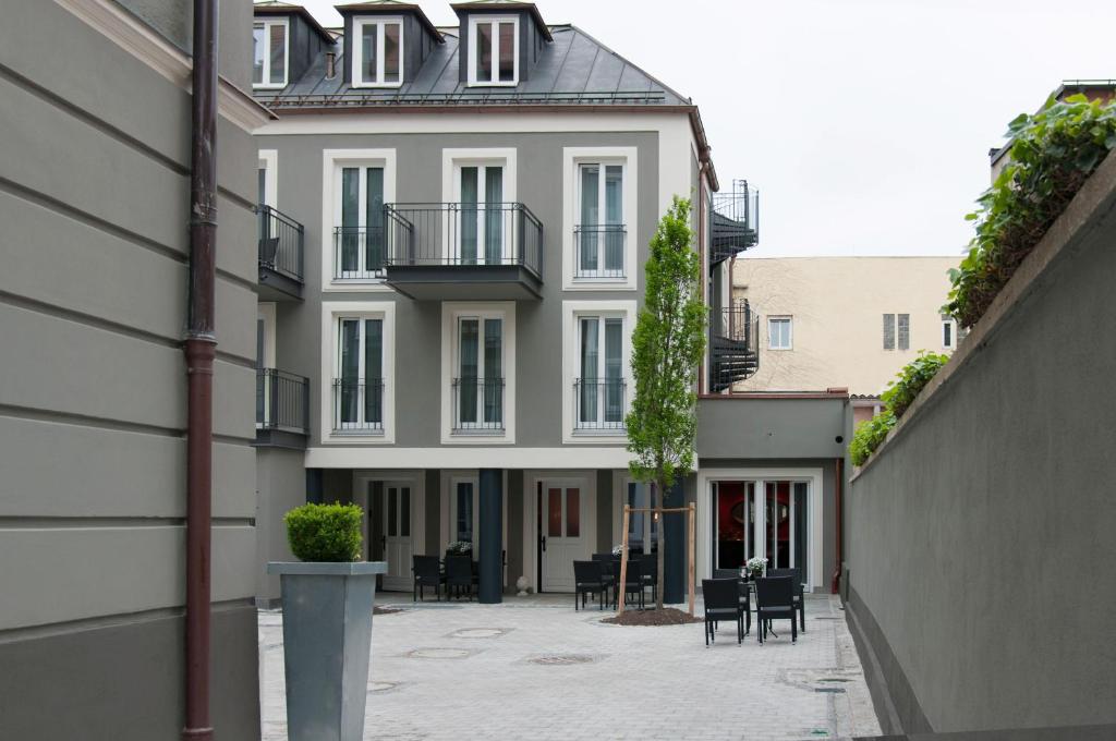 - un bâtiment blanc avec une cour dotée de tables et de chaises dans l'établissement Hotel im Hof, à Munich