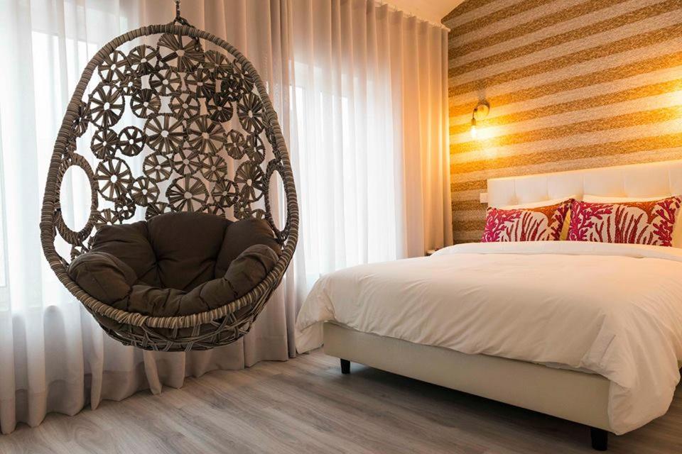 um quarto com uma cadeira suspensa ao lado de uma cama em Home Sweet Praia na Nazaré