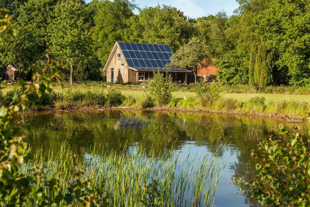 een huis met zonnepanelen op het dak naast een meer bij het Atelier in Eext