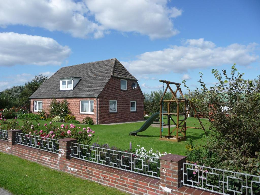 een huis met een tuin en een speeltuin bij Haus Heverstrom in Westerhever