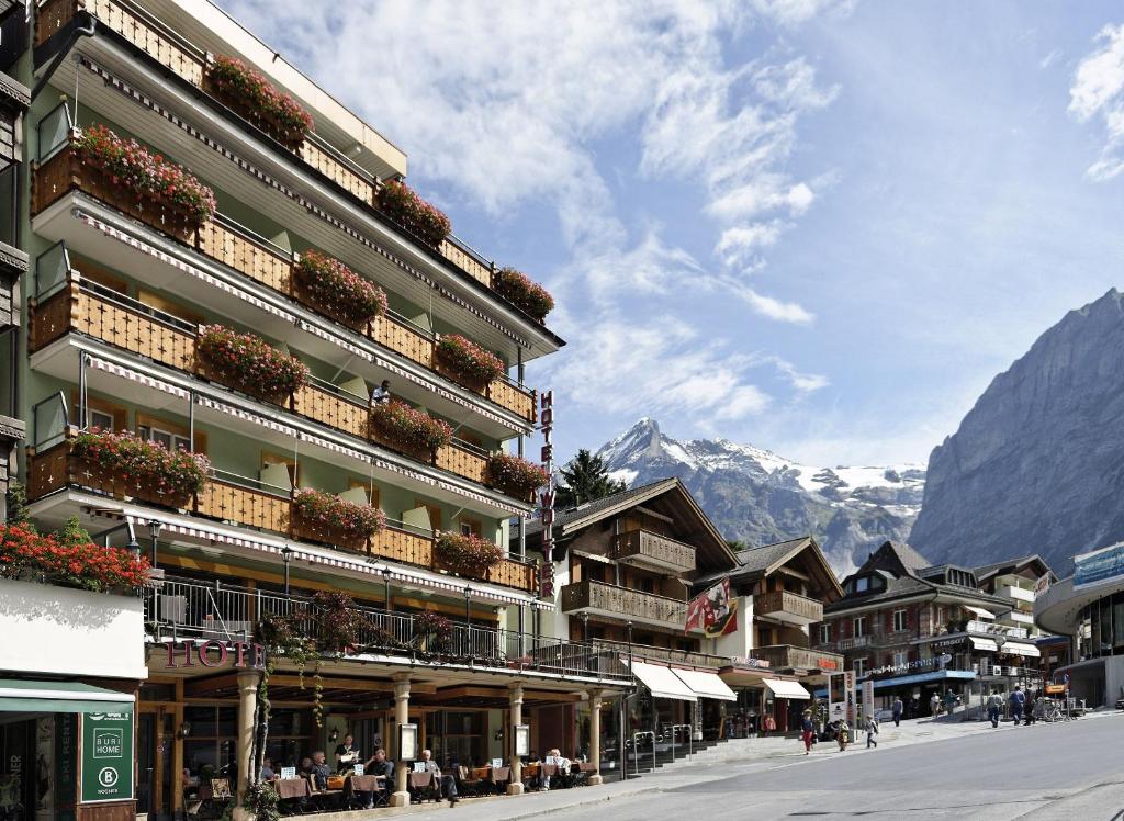 un bâtiment dans une rue avec des montagnes en arrière-plan dans l'établissement Hotel Central Wolter - Grindelwald, à Grindelwald