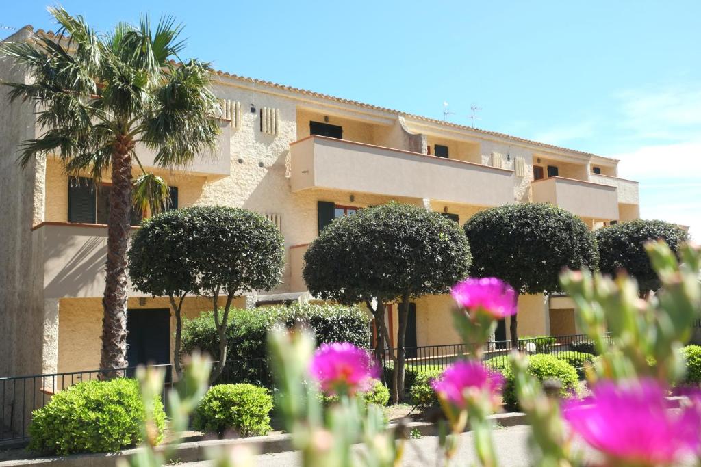 un edificio con una palma e fiori rosa di Blu Baita a La Maddalena