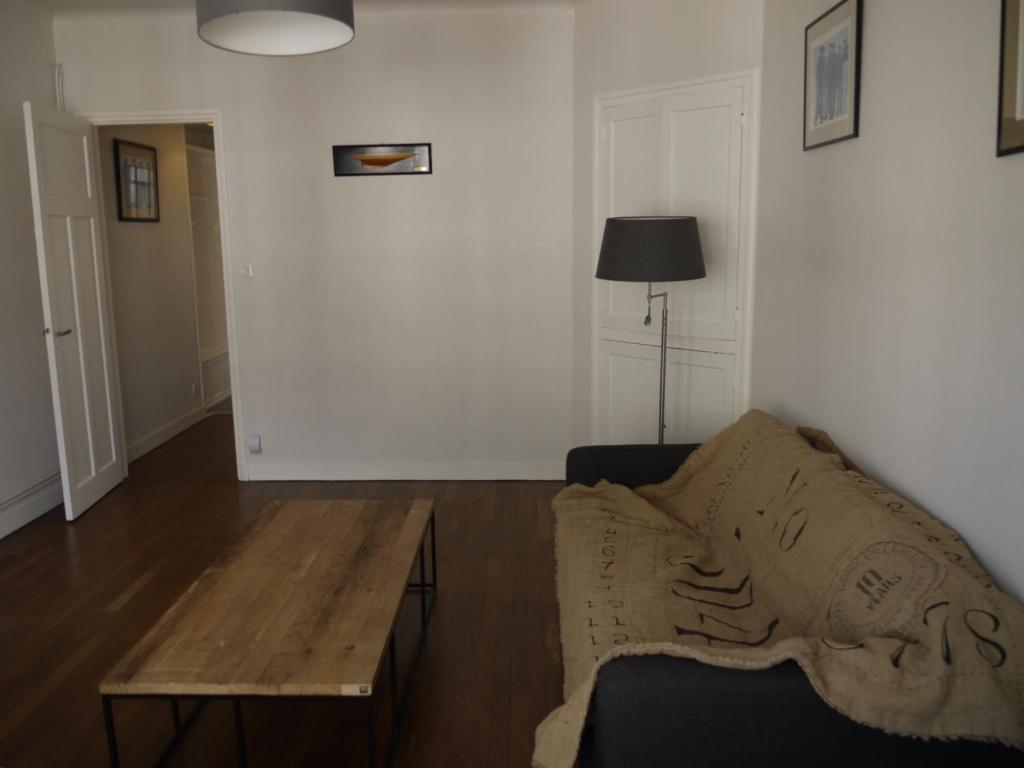 een woonkamer met een bank en een houten tafel bij Appartement Chaussee du Sillon in Saint-Malo