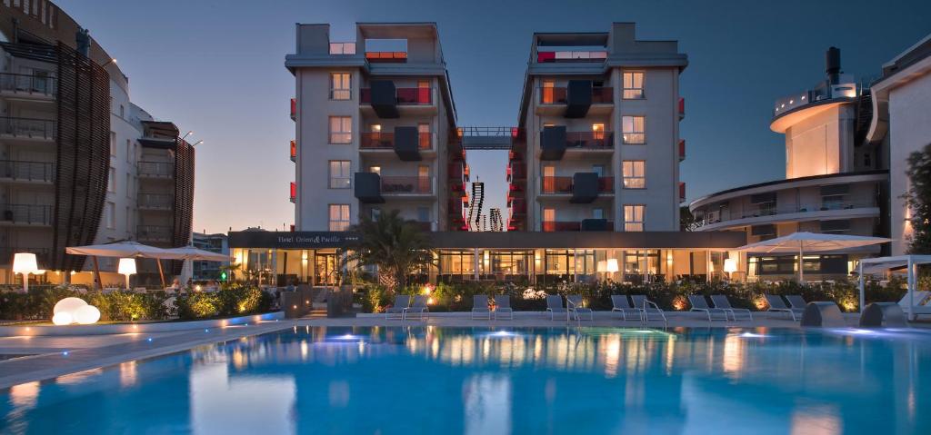 uma piscina em frente a alguns edifícios em Hotel Orient & Pacific em Lido di Jesolo