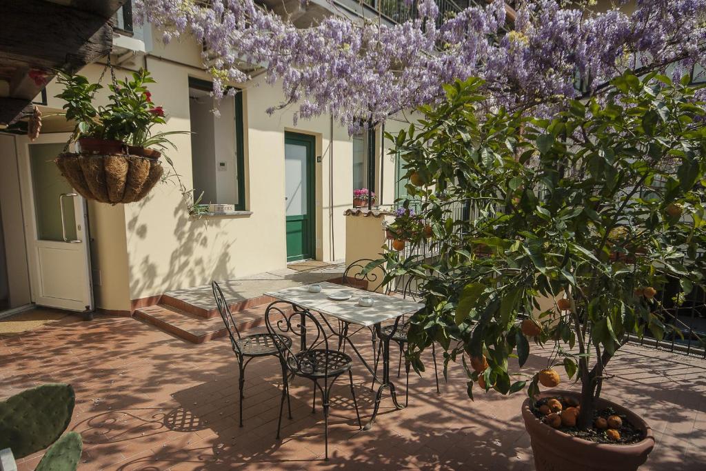 un patio avec une table et des chaises et un arbre avec des fleurs violettes dans l'établissement Antica Corte, à Busto Arsizio