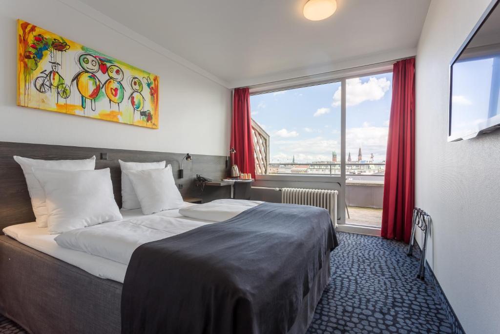 Cette chambre comprend un lit et une grande fenêtre. dans l'établissement ProfilHotels Mercur, à Copenhague