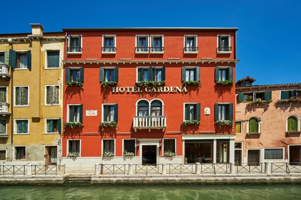 un edificio rosso sul lato di un fiume di Hotel Gardena a Venezia