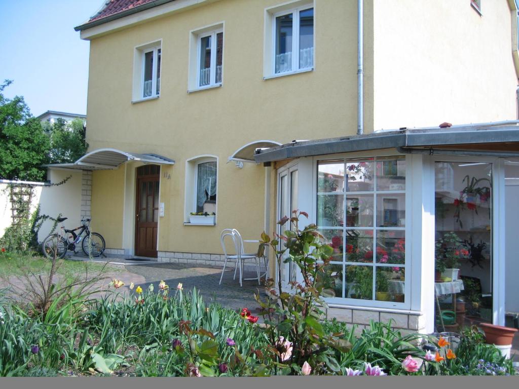 una casa gialla con un giardino d'inverno di fronte di Pension Alter Zausel a Weimar