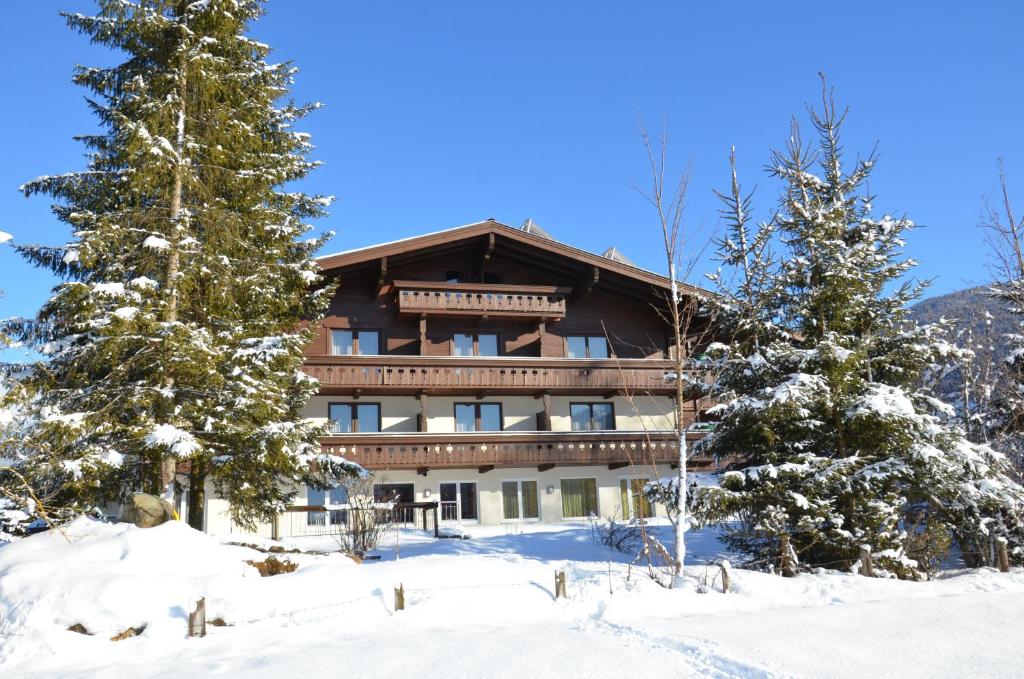 un grand bâtiment dans la neige avec des arbres dans l'établissement Hotel Wieser, à Mittersill