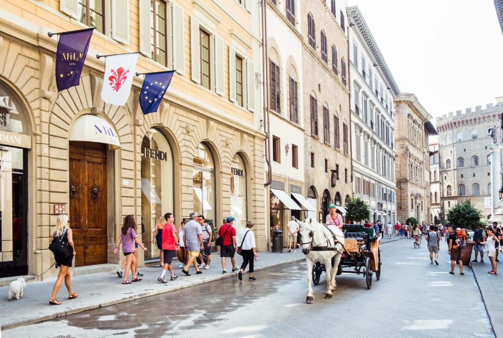 un carruaje tirado por caballos en una calle de la ciudad con gente en Hotel Milu Florence, en Florencia