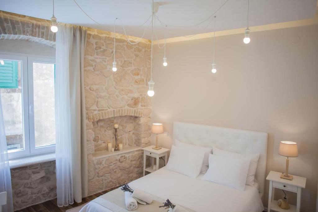 ein Schlafzimmer mit einem weißen Bett und einer Steinmauer in der Unterkunft Barone Room in Šibenik